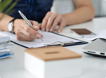 Person writing on clipboard at desk.